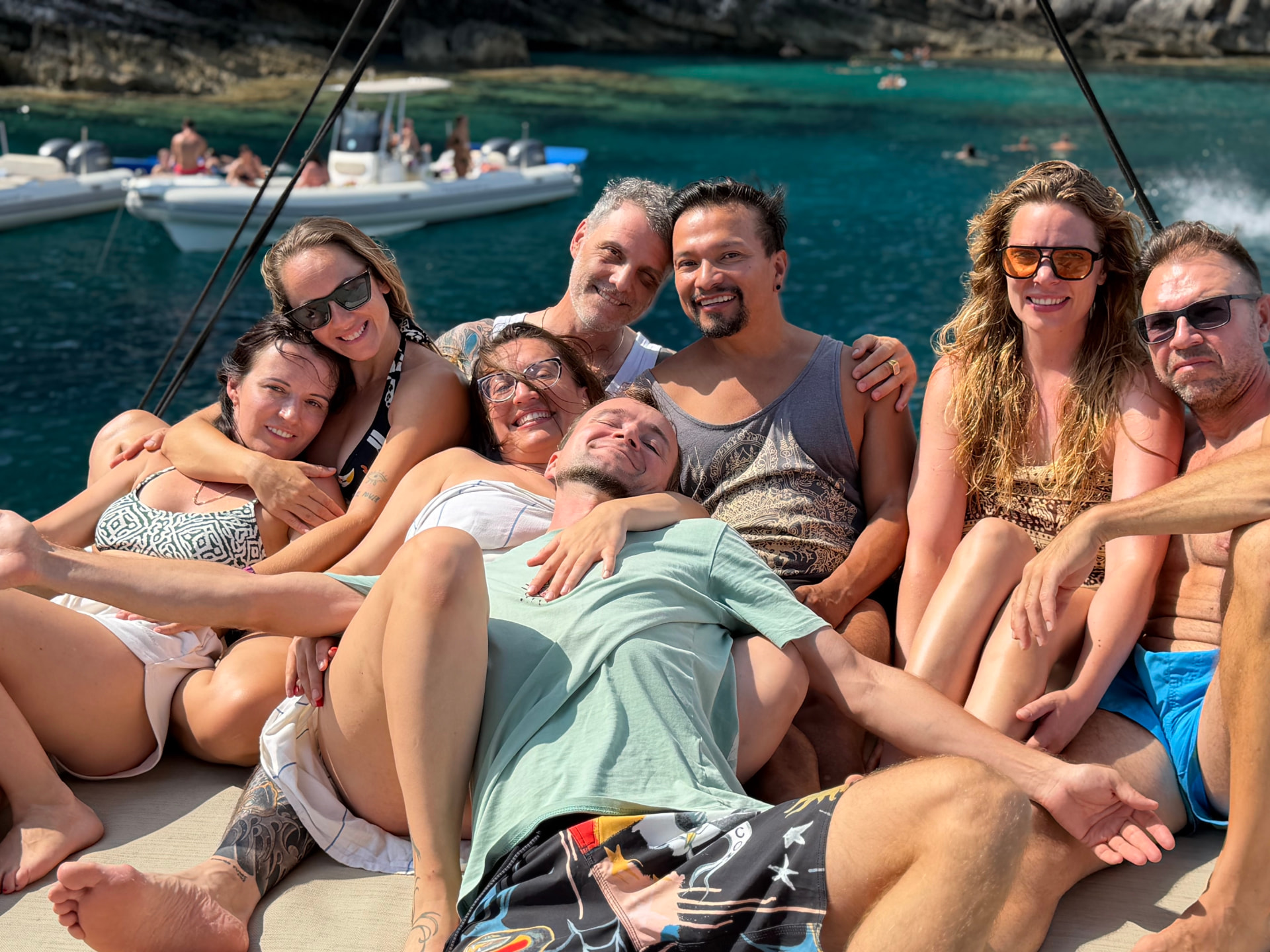 Friends relaxing and laughing together on the sun deck of a catamaran in a turquoise bay